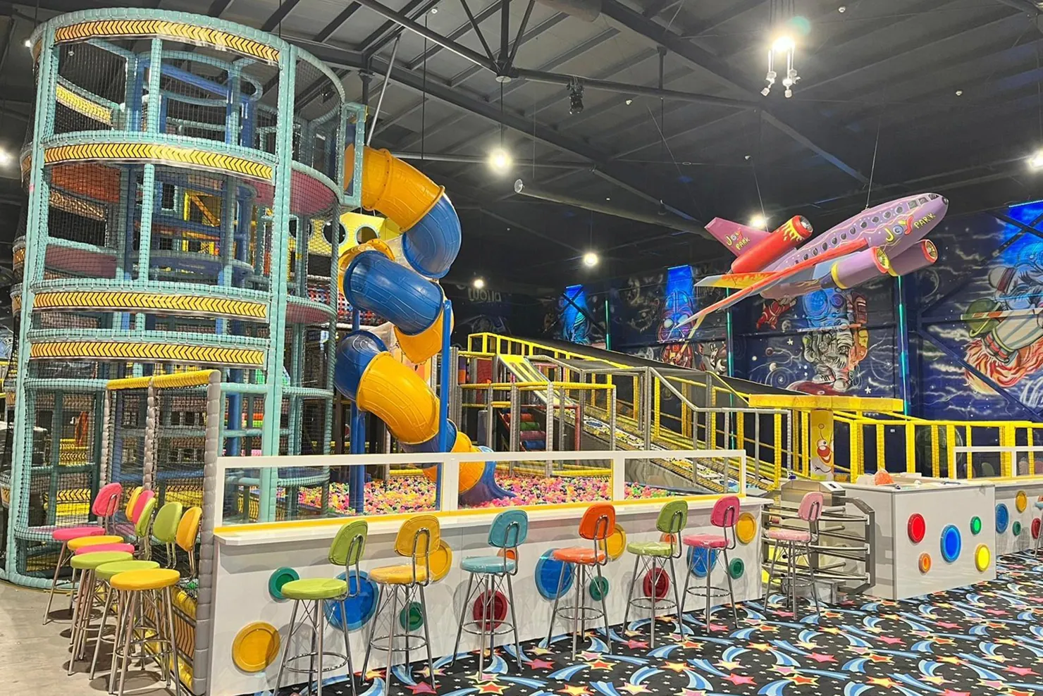 Wide view of an indoor entertainment venue with custom slides and airplane installation