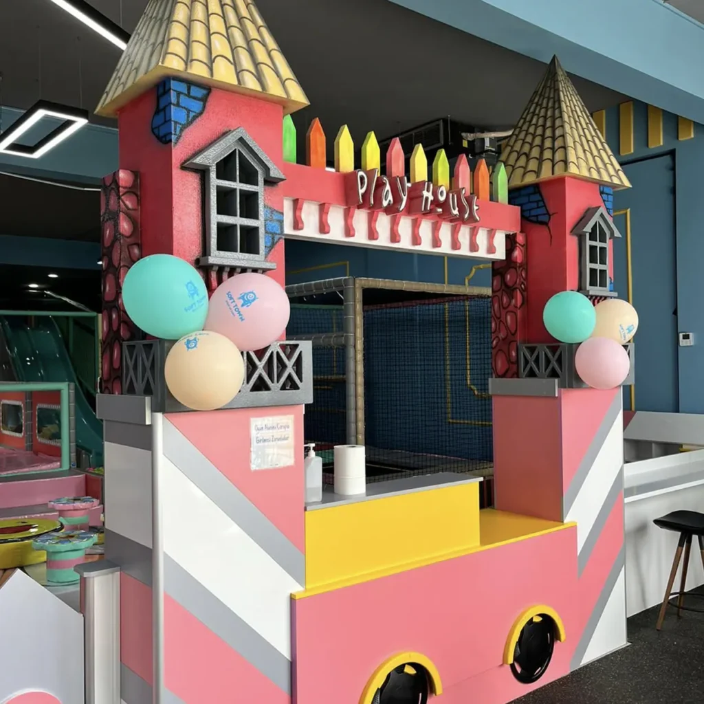 Whimsical pink playhouse entrance with castle towers and colorful balloons