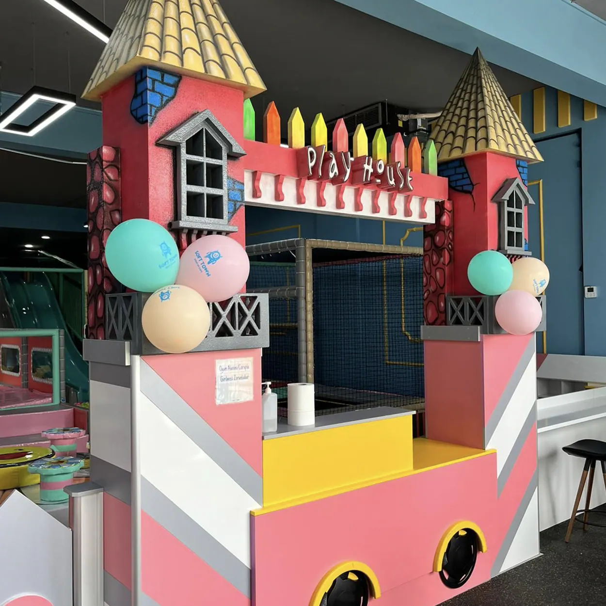 Whimsical pink playhouse entrance with castle towers and colorful balloons